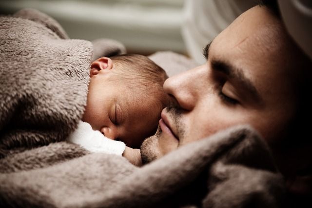 Spící mladý muž s miminkem pod dekou