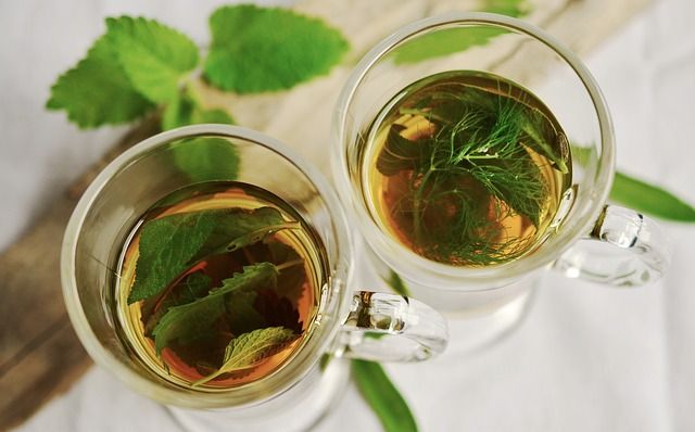 Zalitý bylinkový čaj ve skleněných hrnečkách